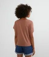 Blusa color marrón claro estilo t-shirt, con cuello redondo y mangas cortas. Presenta un bordado de cocotero en el frente.
