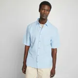 Camisa celeste de lino con corte regular, cuello clásico y manga corta.