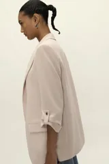 Blazer blanco con cuello solapa y hombreras. Manga por debajo del codo acabada en vuelta con trabilla y botón dorado. Bolsillos delanteros con solapa.