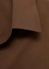 Camisa marrón de corte recto, con cierre de botones en la parte delantera, cuello camisero y mangas largas con puños abotonados.