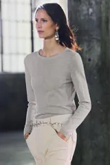 Sweater color beige de tejido de punto fino, con cuello redondo y mangas largas.