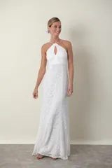 Vestido largo de encaje blanco, con breteles finos cruzados en la espalda y escote halter con abertura en forma de gota.