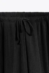 Pantalón bombacho negro de tiro alto con cintura elástica ajustable con cordones y puños elásticos en los tobillos.