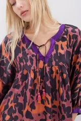 Camisa de corte amplio con estampado animal print en tonos naranja, marrón y violeta, con escote en V con lazos para atar y mangas 3/4 abullonadas.