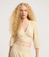 Blusa corta de encaje guipir de algodón con escote en V, botones frontales y manga larga abullonada con puño elástico.