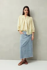Camisa celeste a rayas verticales, de corte amplio y mangas 3/4. Presenta cuello mao, cierre frontal con botones irregulares y detalle de pespuntes y pinzas en el canesú.