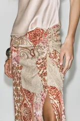 Falda midi de tiro alto con estampado paisley en tonos beige, rosa y marrón. Presenta frunces y cordón lateral, abertura en el bajo y cierre lateral con cremallera oculta.