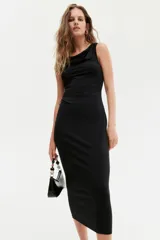 Vestido midi negro sin mangas en punto elástico con leve brillo. Modelo ajustado con frunces en escote, hombros y en un lateral de la cintura para crear un efecto drapeado.