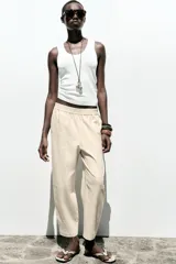 Pantalón bombacho color beige de lino, con cintura elástica, bolsillos frontales y bolsillos de parche en la espalda.
