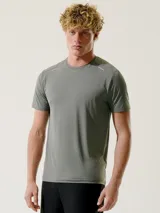 Remera deportiva verde con cuello redondo y mangas cortas. Presenta detalles reflectantes en los hombros.