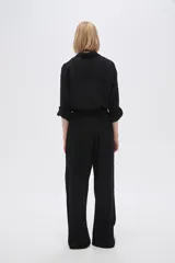 Pantalón ancho de viscosa color negro, con calce alto y bolsillos laterales.