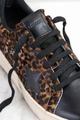 Zapatilla de cuero con diseño de animal print en tonos marrón y negro, con suela clara.