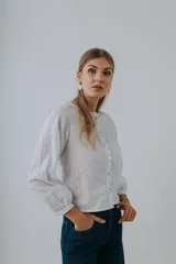 Camisa blanca con bordado floral, cuello redondo y cierre frontal con botones.