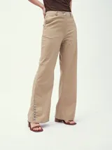 Pantalón de vestir color beige, de corte palazzo, con cintura alta y detalle de botones en el ruedo.