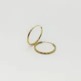 Aros tipo argolla de plata 925 con baño de oro, presentando una textura facetada o labrada en toda su superficie.