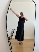 Vestido largo azul marino de tejido acanalado, con escote redondo y mangas cortas tipo hombrera. Presenta una abertura lateral en la falda.