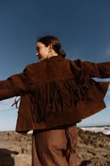 Chaqueta marrón de cuero gamuzado con flecos en la parte delantera y trasera.