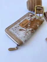 Billetera de cuero con diseño de pelo color beige, incluye cierre metálico y monedero interno.