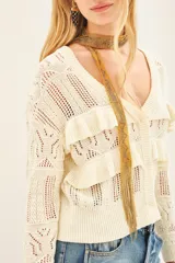 Cardigan color crema tejido en punto desagujado con volados tejidos en rib, calce crop y silueta ancha.