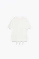 Camiseta blanca de algodón con cuello redondo, manga corta y volantes de gasa en el frente.