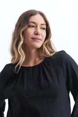 Blusa blanca de manga larga con detalle de tablas en el frente y puños.