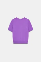 Jersey de punto negro, cuello redondo y manga corta, con acabados en rib en cuello, puños y ruedo.