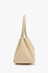 Bolso tipo city color beige, con doble asa corta y compartimento interno con cierre.