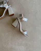 Sandalias plateadas con tira delantera, tobillera con hebilla y taco geométrico.