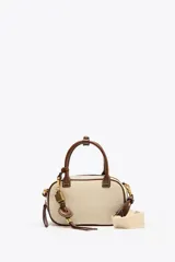 Bolso mini color crudo con detalles en marrón. Tiene asa de mano y doble asa bandolera extraíble, una en tejido tipo canvas y otra con pespunte. Incluye charm con piezas metálicas y bolsillo interior con cremallera.
