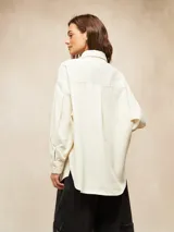 Camisa de pana fina color crudo, con cuello camisero, botones negros y mangas largas abullonadas con puños.