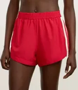Short deportivo femenino modelo runner, color marrón chocolate con cintura elástica y rayas laterales color crema.