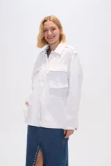 Chaqueta blanca de algodón con cuello camisero, cierre frontal con botones, bolsillos de parche y frunces en los hombros.