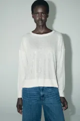 Sweater de punto calado color blanco, de corte holgado, cuello redondo y manga larga.