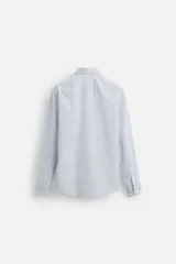 Camisa de hombre regular fit confeccionada en tejido de algodón a rayas verticales azules y blancas. Tiene cuello italiano, manga larga con puños abotonados y cierre frontal con botones.