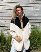 Buzo tipo poncho de polar color crudo con bloque superior en negro y detalles en beige.