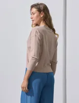 Cárdigan color beige tejido en hilado fino, con escote en V y cierre frontal con un botón.