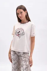 Remera color crudo de manga corta con cuello redondo y ribete marrón. Estampa frontal de Mickey Mouse con texto "Global Explorer Since 1928".