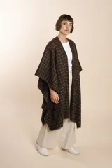 Ruana marrón con diseño a cuadros blancos, terminación envivada y flecos cortos.