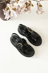 Sandalias bajas color marrón de cuero gamuzado, con tiras cruzadas y hebilla metálica.