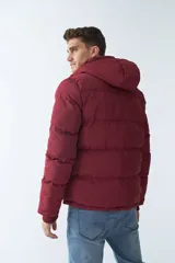 Campera puffer negra de nylon con capucha ajustable, cierre frontal con botones a presión y bolsillos laterales.