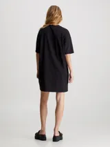 Vestido corto negro de corte recto, con cuello redondo y mangas cortas. Estampado vertical con el logo de Calvin Klein Jeans en color blanco.