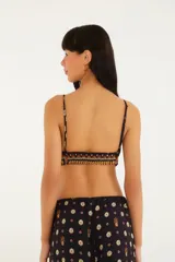 Top negro con estampado de pañuelo en tonos naranja, amarillo y rosa. Tiene tirantes finos regulables y corte triangular.