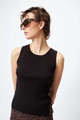 Musculosa de punto color beige, con textura acanalada y detalle de trenzado lateral ajustable.