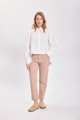 Camisa celeste a rayas verticales, con cuello clásico, cierre frontal con botones, mangas largas abullonadas y corte asimétrico.