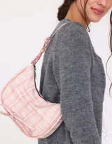 Bandolera de cuerina estampada con diseño escocés en tonos rosa y blanco. Presenta frunce y lazo frontal con moño, manija superior regulable con hebilla y cierre superior.