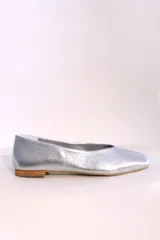 Bailarina blanca de diseño minimalista con punta afilada y suela de madera.
