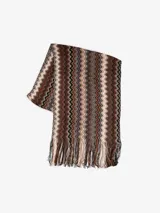 Bufanda tipo chalina de tejido de punto con diseño de ondas en tonos marrón, beige y negro. Tiene flecos en los extremos.