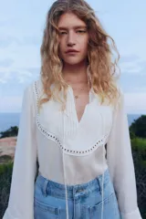 Blusa blanca de corte holgado en tejido transparente de mezcla de lyocell. Modelo de manga larga con cuello elevado de encaje, puños anchos abotonados y bajo recto. Pechera con abertura, alforzas y tiras spaghetti.