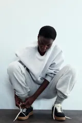 Zapatillas deportivas de mujer con combinación de materiales en negro, blanco y marrón. Cierre con cordones y suela en contraste color caramelo.