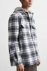 Sobrecamisa relaxed fit de algodón a cuadros azul marino y blanco, con capucha gris combinada a contraste, manga larga con puños abotonados, bolsillos plastrón en el pecho, bolsillos laterales en la cadera y cierre frontal con botones.